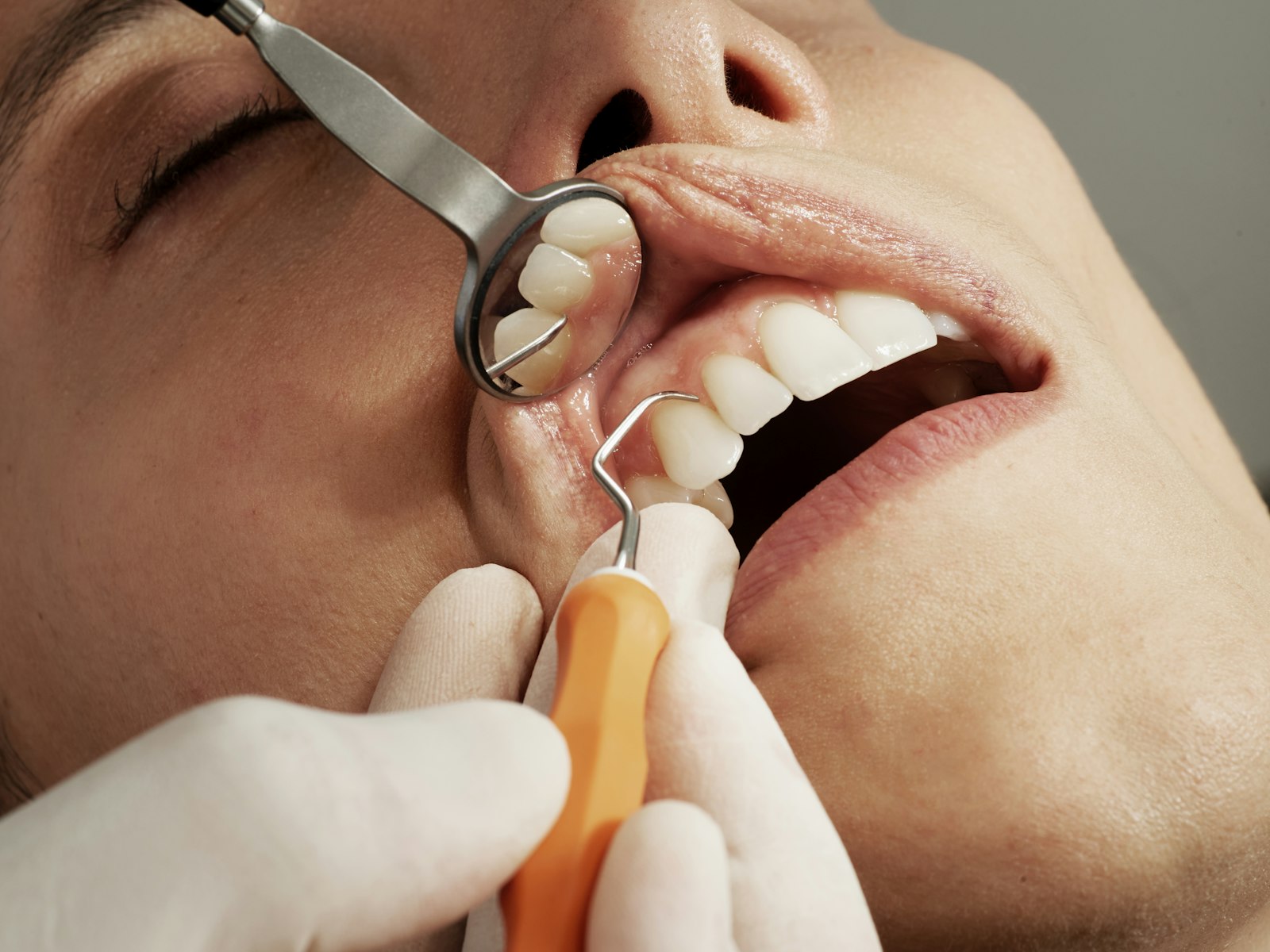A dentist examining a patient's teeth with a mirror, in soft grey light
